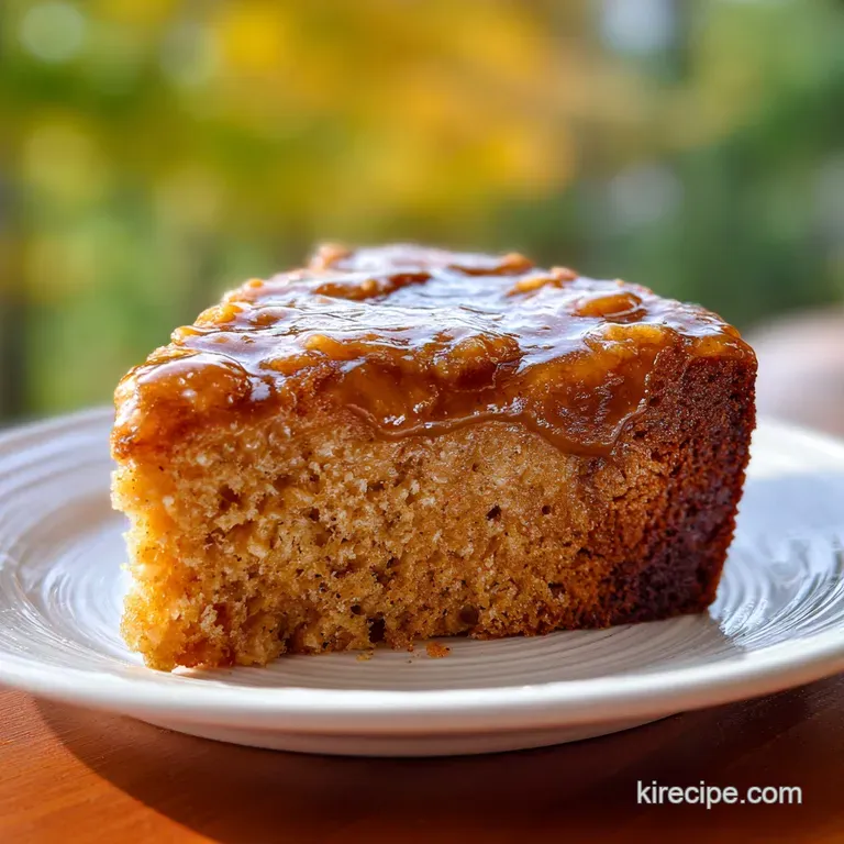 Slice of moist apple oatmeal cake on a white plate, topped with a dollop of cream. Cinnamon dusting adds warmth.