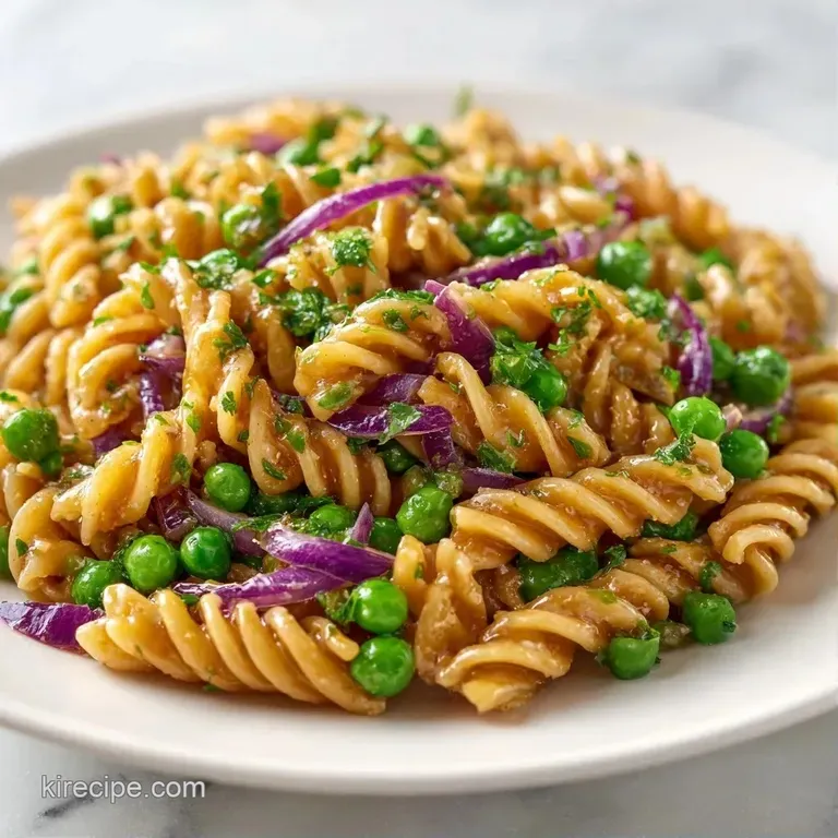 Elegant plate of twisted pasta tossed with herbs and lemon zest, accented by a fresh lemon wedge on the side.