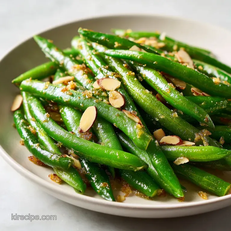 Neatly piled bright green beans topped with toasted almond slivers served in a clean, modern white porcelain bowl.
