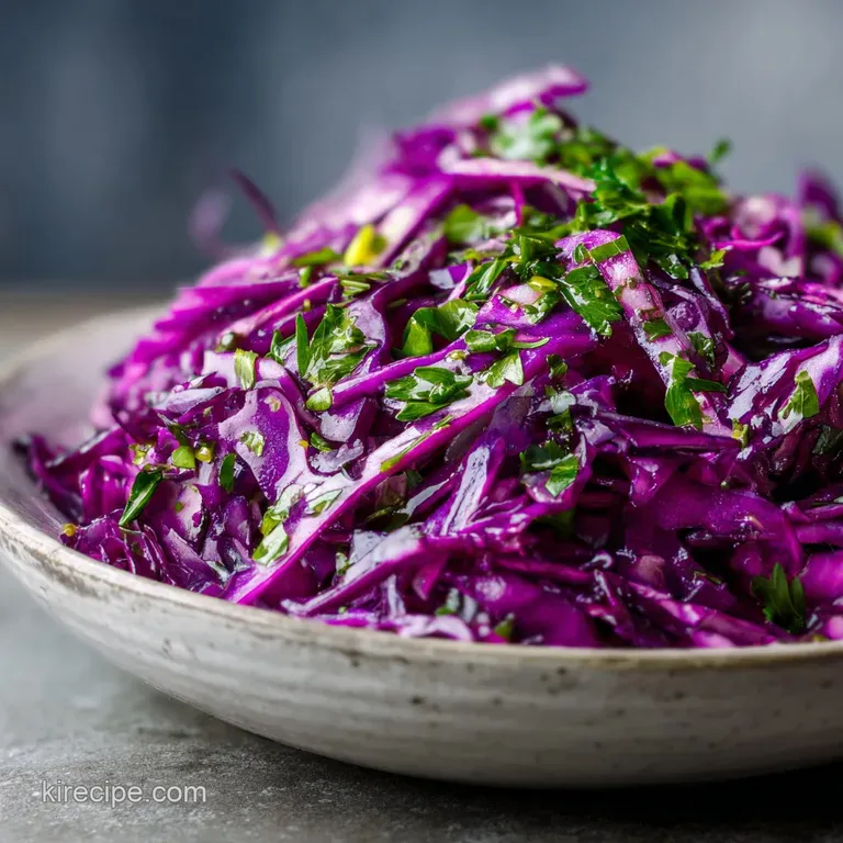 A mound of bright magenta cabbage ribbons on a white ceramic plate, garnished with fresh herbs and sesame seeds.