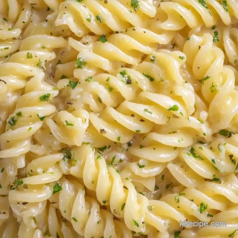 A chilled white platter filled with spiraled pasta, bright red tomatoes, and fresh green herbs in a citrus glaze.